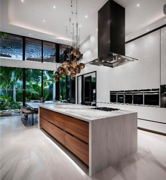 kitchen featuring light stone counters, island exhaust hood, a spacious island, and modern cabinets