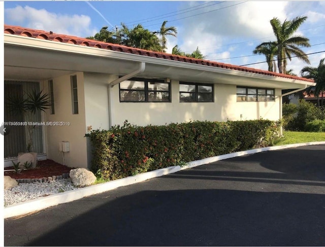 view of side of home with a tile roof and stucco siding