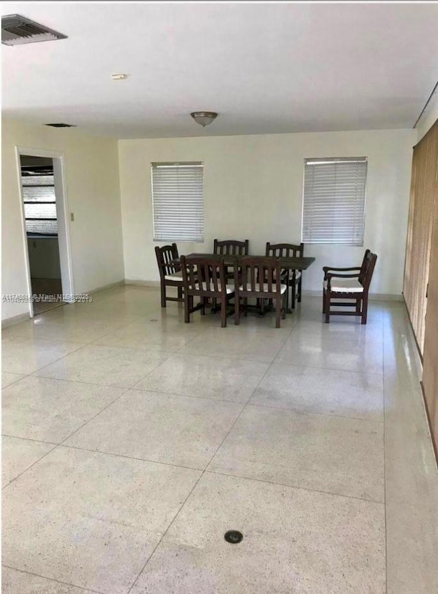 dining area with light speckled floor, visible vents, and baseboards