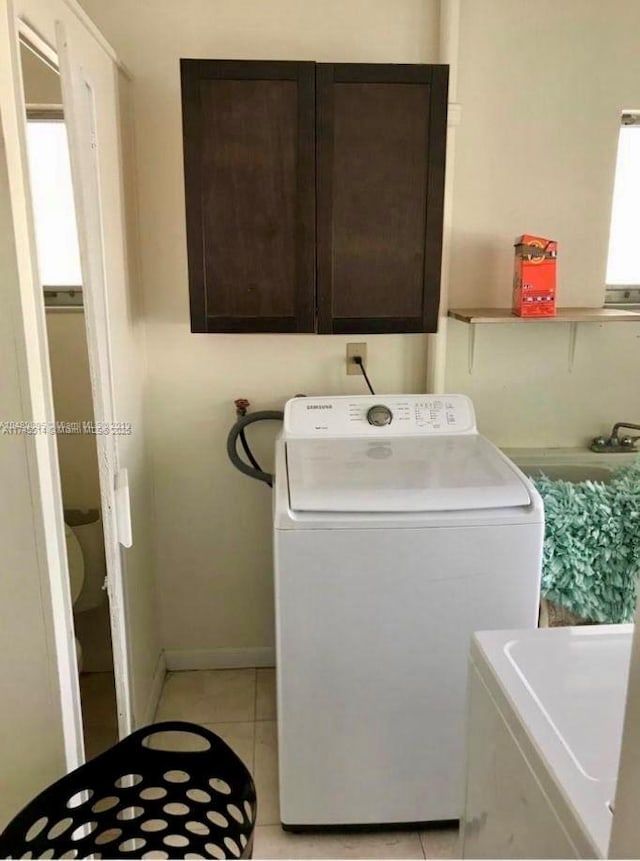 laundry room featuring baseboards, cabinet space, separate washer and dryer, and light tile patterned flooring