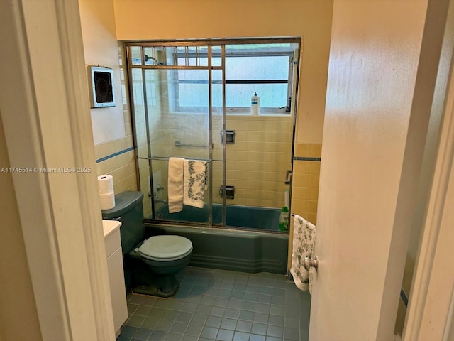 full bathroom featuring tile patterned flooring, vanity, toilet, and bath / shower combo with glass door