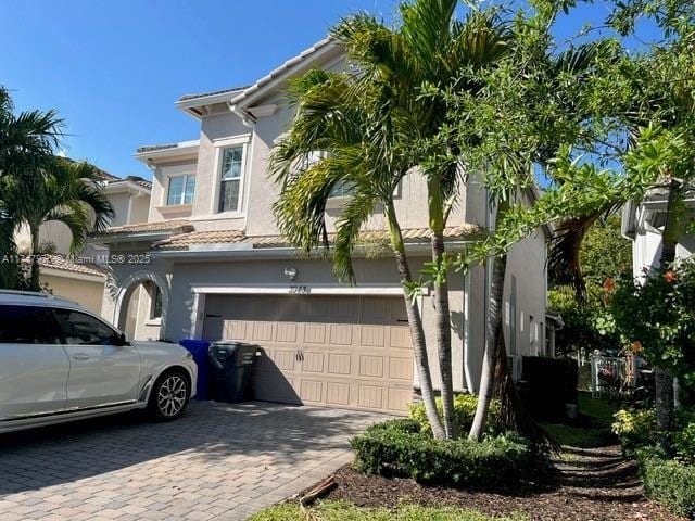 view of front of house featuring a tiled roof, decorative driveway, a garage, and stucco siding