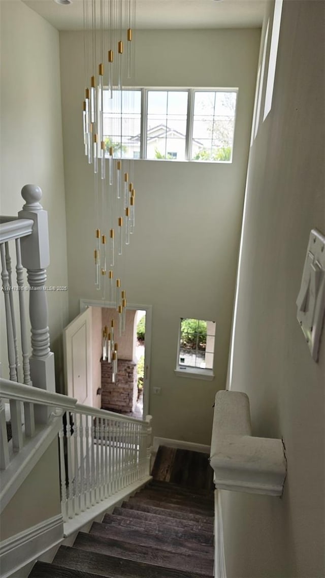 stairway with a high ceiling, wood finished floors, and baseboards