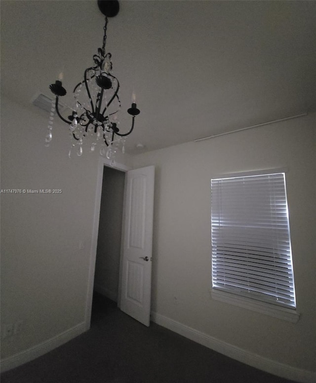 empty room featuring baseboards and an inviting chandelier