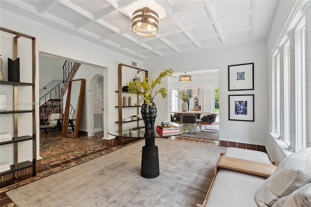 interior space with arched walkways, coffered ceiling, baseboards, stairway, and beam ceiling