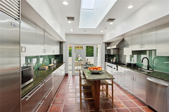kitchen with wall chimney exhaust hood, visible vents, backsplash, and appliances with stainless steel finishes