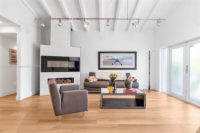 living room with baseboards, beamed ceiling, light wood-type flooring, and track lighting