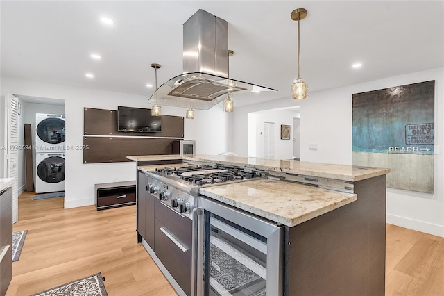 kitchen with wine cooler, a center island, stainless steel gas cooktop, island range hood, and stacked washing maching and dryer