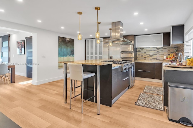 kitchen with island exhaust hood, modern cabinets, decorative backsplash, light wood-style floors, and built in appliances