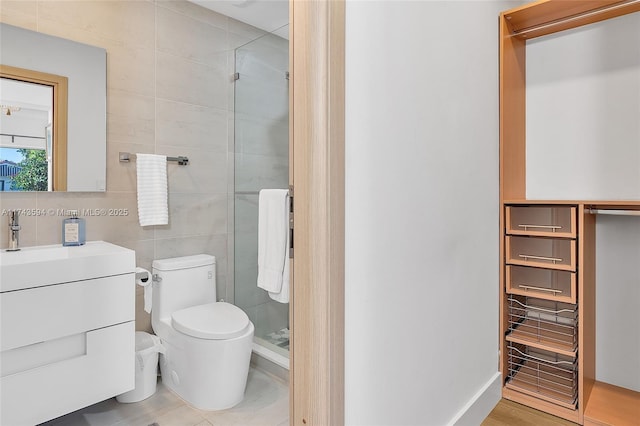 bathroom with a stall shower, toilet, tile walls, and vanity