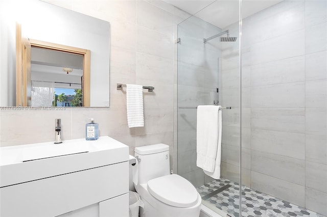 bathroom featuring a stall shower, tile walls, toilet, vanity, and backsplash