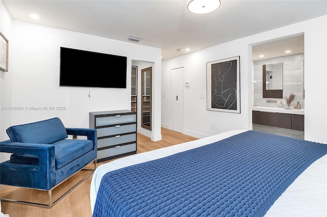 bedroom featuring ensuite bath, light wood-style floors, baseboards, and visible vents