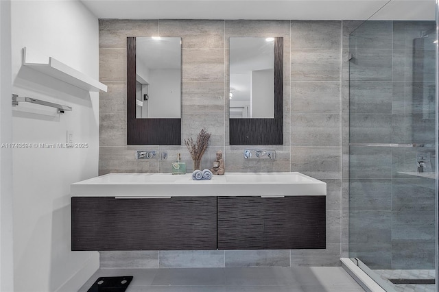 full bathroom with double vanity, a stall shower, backsplash, and tile walls