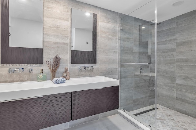 bathroom featuring tile walls, double vanity, decorative backsplash, a sink, and a shower stall