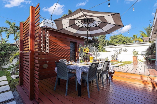 deck featuring outdoor dining area and fence