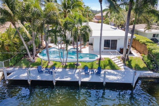 rear view of house featuring stucco siding, a patio area, a fenced backyard, and a water view