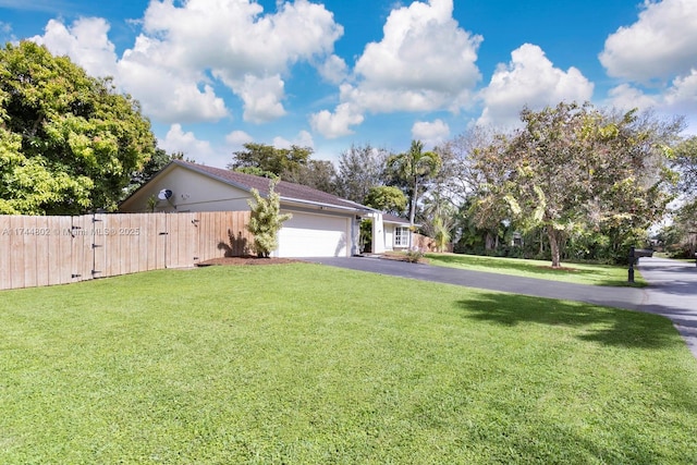 exterior space with a garage, driveway, a front lawn, and fence