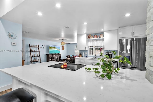 kitchen with black electric stovetop, white cabinets, stainless steel fridge with ice dispenser, and light stone counters