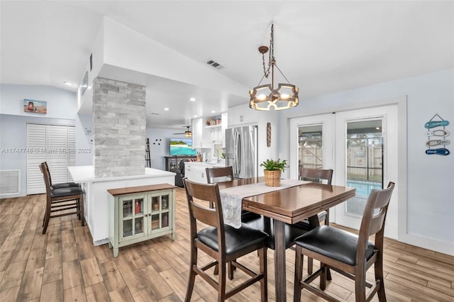 dining area featuring ceiling fan with notable chandelier, light wood-type flooring, lofted ceiling, and french doors