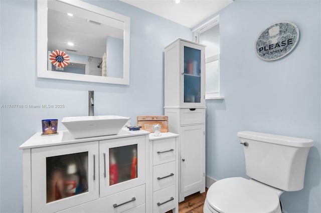 bathroom with wood-type flooring, vanity, and toilet