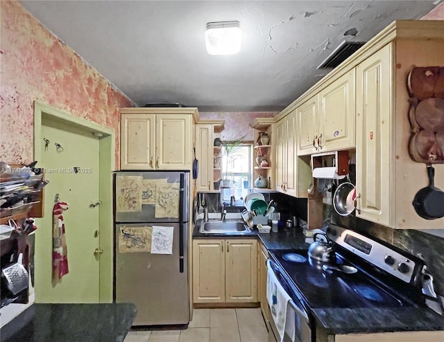 kitchen with appliances with stainless steel finishes, sink, cream cabinets, and light tile patterned floors