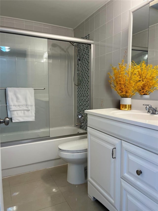 full bathroom featuring toilet, tile patterned floors, combined bath / shower with glass door, vanity, and tile walls