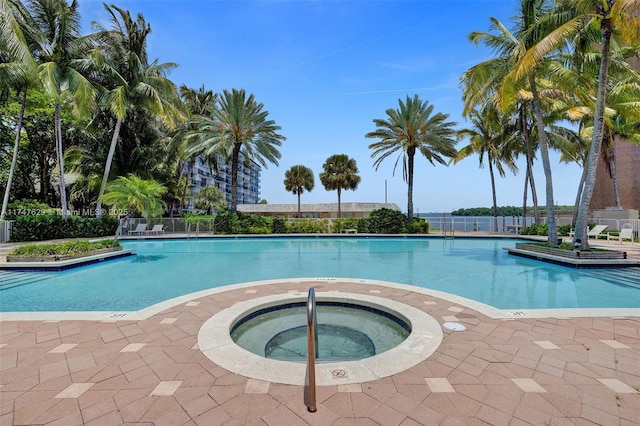 pool featuring fence and a hot tub