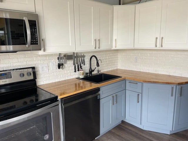 kitchen with tasteful backsplash, appliances with stainless steel finishes, dark wood-style flooring, wooden counters, and a sink