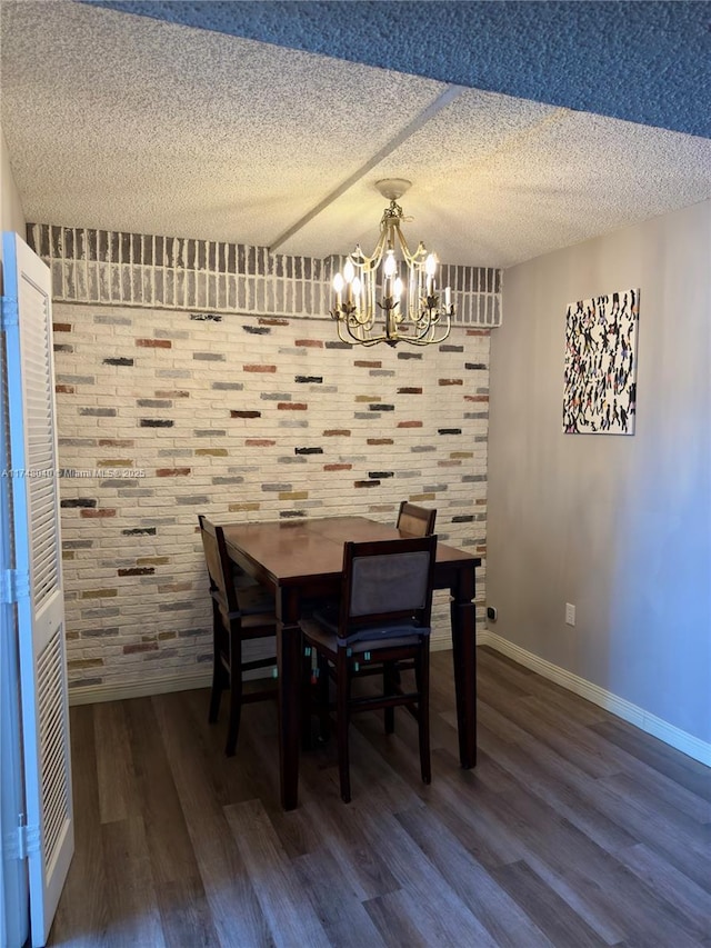 dining room featuring a chandelier, a textured ceiling, baseboards, and wood finished floors