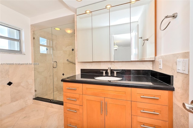 bathroom with tile walls, a shower with door, and vanity