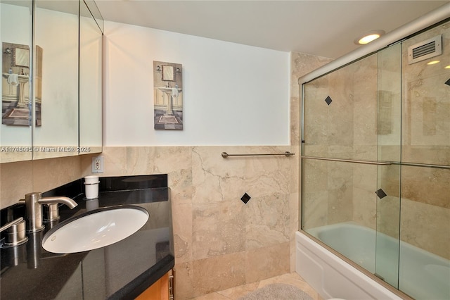 bathroom with tile walls, vanity, and enclosed tub / shower combo