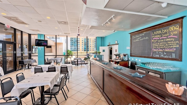 kitchen featuring a wall of windows, a drop ceiling, and light tile patterned floors