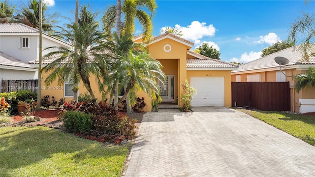 mediterranean / spanish home featuring a garage and a front lawn