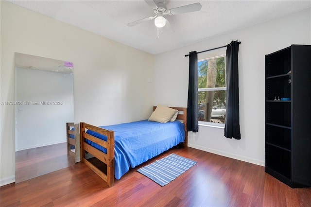 bedroom with dark hardwood / wood-style flooring, ceiling fan, and a textured ceiling