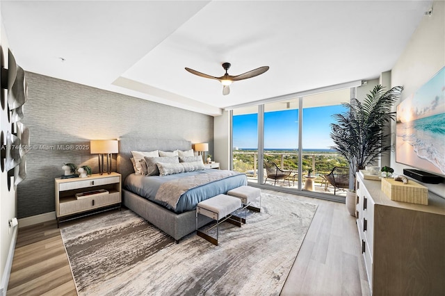 bedroom with hardwood / wood-style flooring, ceiling fan, floor to ceiling windows, and access to exterior