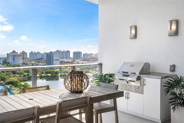 balcony featuring a water view, an outdoor kitchen, and a grill