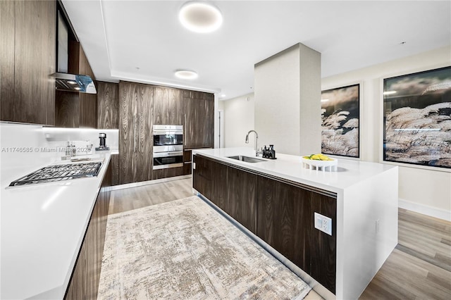 kitchen featuring a center island with sink, light hardwood / wood-style floors, stainless steel appliances, and sink