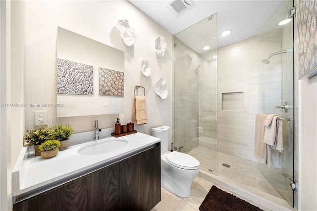 bathroom with tile patterned floors, toilet, vanity, and a shower with door