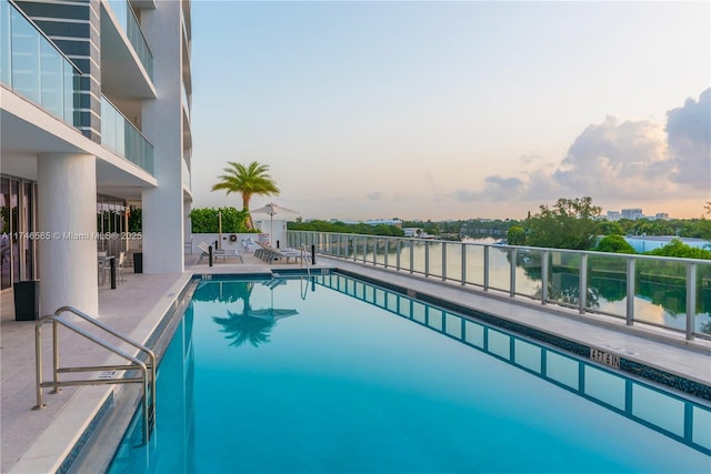 pool at dusk with a patio area