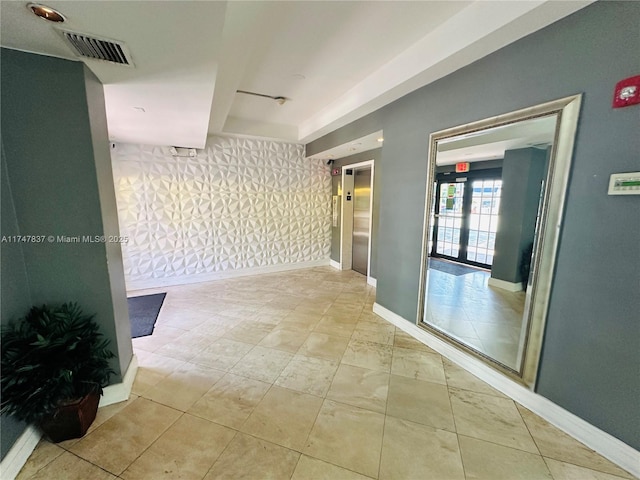 corridor featuring elevator, visible vents, and baseboards