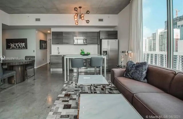 living room with a notable chandelier and concrete floors