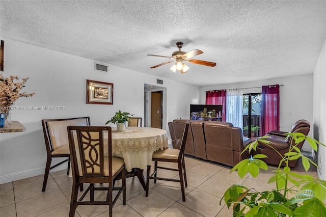 tiled dining space with a textured ceiling and ceiling fan