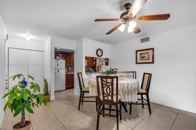 tiled dining area with ceiling fan and a textured ceiling