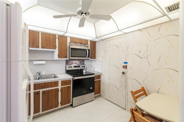 kitchen featuring stainless steel appliances, a sink, visible vents, light countertops, and brown cabinetry