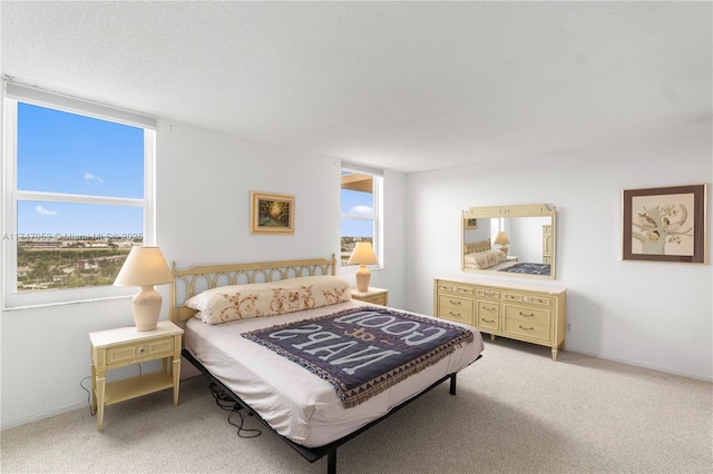 bedroom with light colored carpet, a textured ceiling, and baseboards