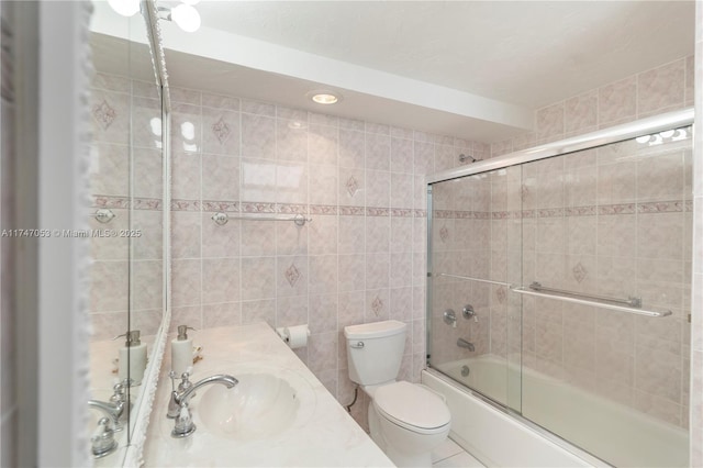 full bath featuring toilet, shower / bath combination with glass door, tile walls, and vanity