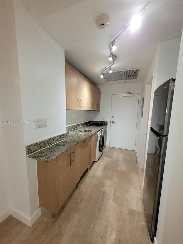 10275 Collins Ave Unit 111, Bal Harbour, FL 33154 - kitchen featuring sink, rail lighting, dark stone counters, washer / clothes dryer, and black refrigerator