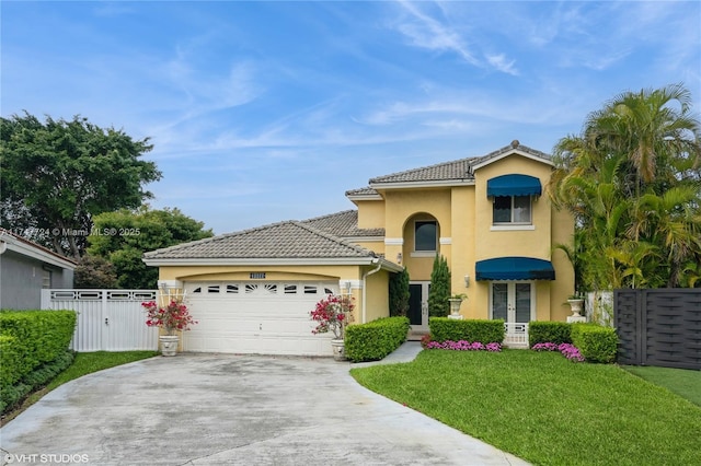 mediterranean / spanish home with a garage, concrete driveway, a tiled roof, stucco siding, and a front yard