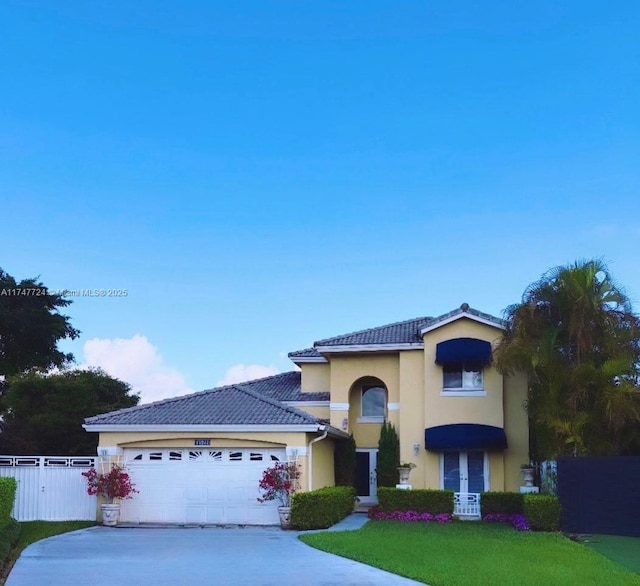 view of front of home featuring an attached garage, fence, driveway, a tiled roof, and stucco siding