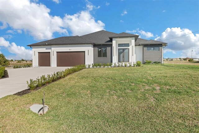 prairie-style house featuring concrete driveway, a front lawn, and an attached garage